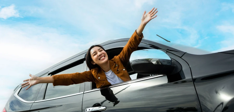 A confident driver loading a bag into the open trunk of their SUV at a scenic pullout
